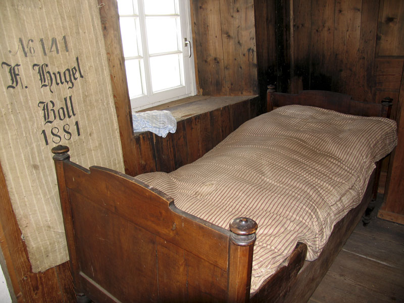 altes Holzbett mit Bettwäsche im Mühlenmuseum Boll im Schwarzwald